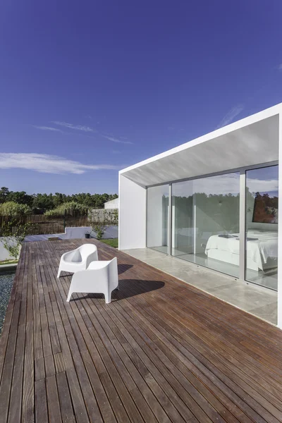 Bahçe havuzu ve ahşap güvertesi olan modern bir ev.