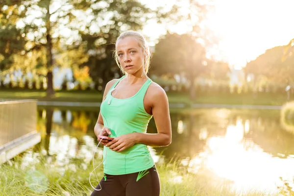 Vrouw met mobiele telefoon klaar voor opleiding in stedelijk park — Stockfoto