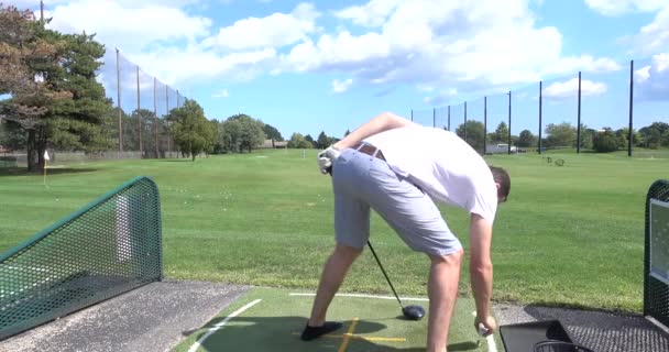 Jongeman slaat golfballen op een driving range — Stockvideo