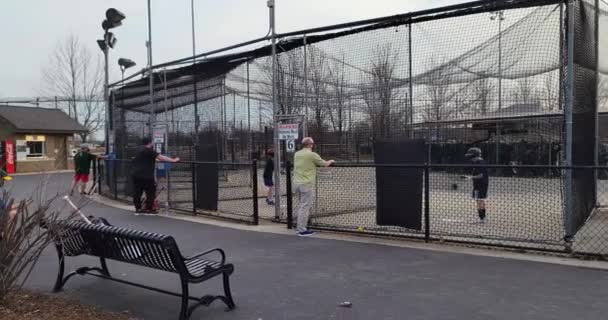 Kinderen en ouders genieten van een aangename, vroege voorjaarsavond in een openbare slagkooi — Stockvideo