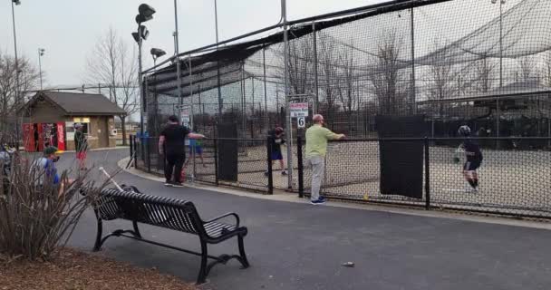 Kinderen en ouders genieten van een aangename, vroege voorjaarsavond in een openbare slagkooi — Stockvideo