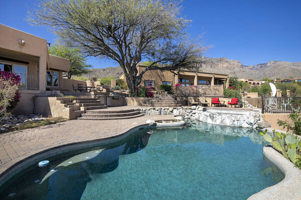 Swimming pool with hot tub and terraced patio at a luxury home in a desert environment.