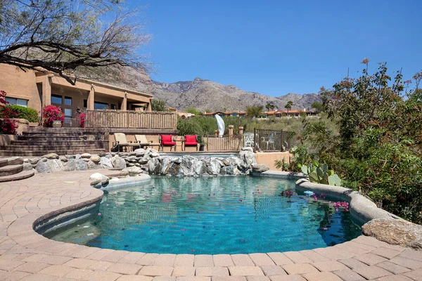 Swimming pool with hot tub and terraced patio at a luxury home in a desert environment.