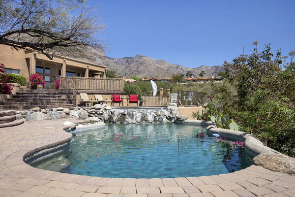 Swimming pool with hot tub and terraced patio at a luxury home in a desert environment.