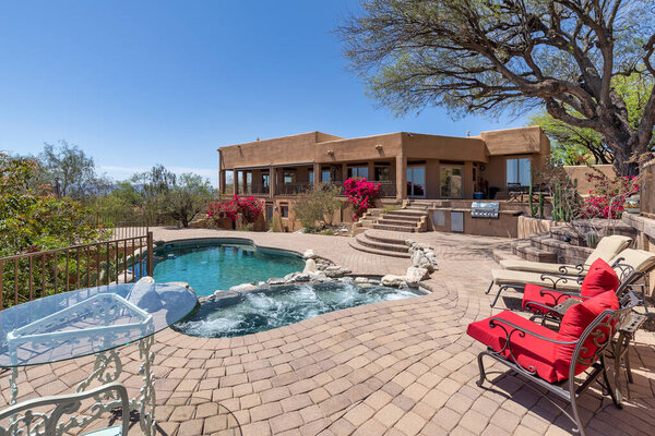 Swimming pool with hot tub and terraced patio at a luxury home in a desert environment.