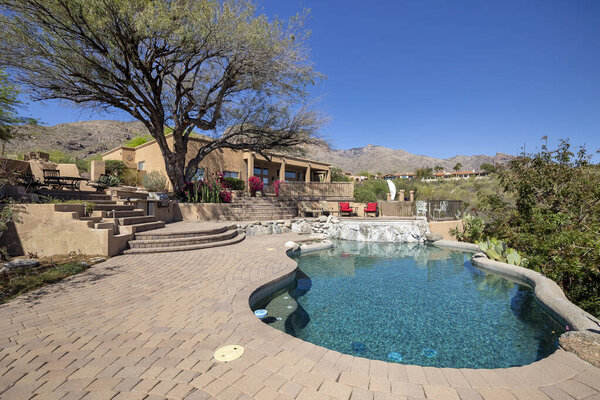 Swimming pool and terraced patio at a luxury home in a desert environment.