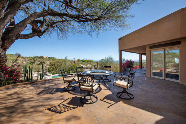 Eating area on a terraced patio with swimming pool at a luxury home in a desert environment.