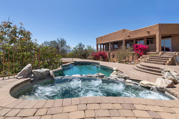 Swimming pool with hot tub and terraced patio at a luxury home in a desert environment.