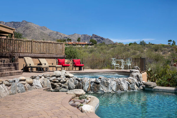 Swimming pool with hot tub and terraced patio at a luxury home in a desert environment.