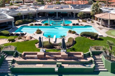 Indian Wells, CA 'deki lüks bir mahallede yüzme havuzu ve tenis / yankesicilik sahası olan büyük, lüks bir evin hava manzarası..