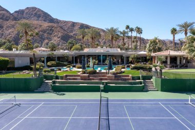 Palm Springs yakınlarındaki Indian Wells 'in lüks bir mahallesinde yüzme havuzu ve tenis / yankesicilik sahası olan büyük, lüks bir malikane manzarası..