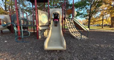 Pembe etekli ve diz boyu çizmeli şık bir kadın oyun parkından kayıyor.