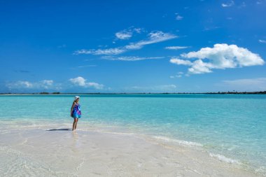 Exumas 'da güneşli bir günde Moriah Harbour Ulusal Parkı' nın ortasındaki bir kumsalda turkuvaz sularının keyfini çıkaran bir kadın..