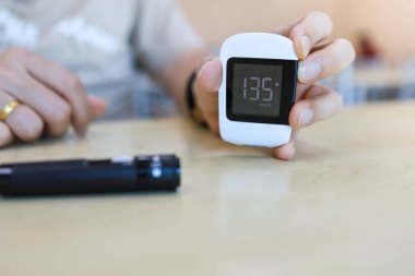 Şeker hastalığı, glisemi, sağlık hizmetleri ve insanların konseptini kullanarak tahta masa üzerinde suni glikoz ölçer tutan adama yakın çekim.