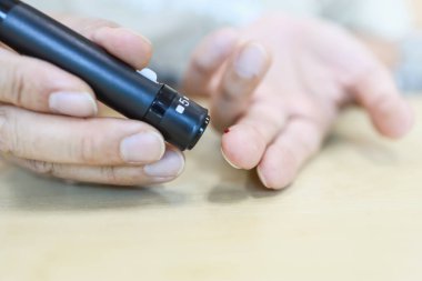 Kan şekeri seviyesini Glikoz ölçer 'e göre ölçmek için parmak üzerine mızrak kullanan erkek elleri. İlaç, diyabet, glisemi, sağlık hizmetleri ve insanların konsepti olarak kullan.