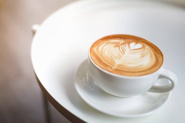 Süt köpüklü sütlü sütlü sütlü sütlü sütlü sütlü kahve fincanına yakın beyaz masada fotokopi alanı olan sanat eseri..