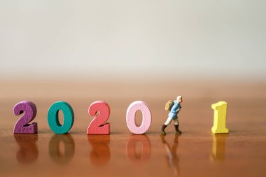 Yeni Yıl 2021 Seyahat ve Seyahat Konsepti. Gezgin minyatür figürler. Sırt çantalı insanlar ahşap masada renkli ahşap numaralarla yürüyorlar..