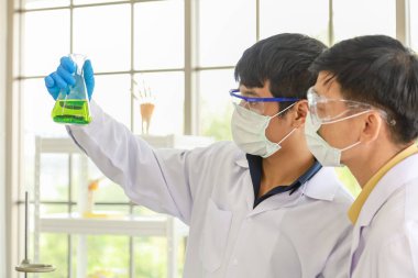 Bilim ve Sağlık Konsepti. İki doktor bir laboratuarda deney tüpleriyle kimyasallar üzerinde çalışıyor..