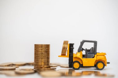 İş, Para ve Finansal Konsept. Mini forklift kamyonet oyuncak model beyaz arka planda altın sikke yığını içerir.