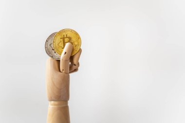 İş, para, teknoloji ve kripto para birimi kavramı. Beyaz arka planda altın ve gümüş bitcoin taşıyan ahşap el modelinin yakın çekimi.