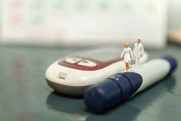 Nurse and Doctor miniature figure with handbag walking on lancet with glucose meter and calender using as diabetes, glycemia, schedule, health care and people concept.
