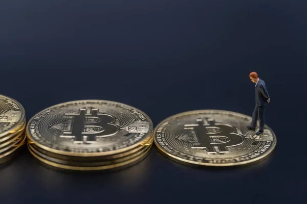 Business , Money, Technology and  cryptocurrency Investment Concept. Closeup businessman miniature figure people standing and walking on of stack of gold bitcoin coins on black background.