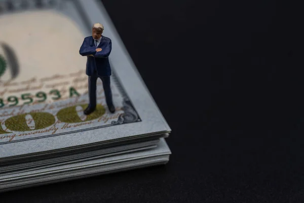 Business, Money, Finance and Information Concept. Businessman miniature figure people standing on stack of 100 US Dollar banknote on black background.