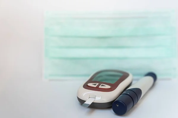 Lancet 수술용 마스크를 배경으로 Glucose Meter 클로즈업 당뇨병 저혈당증 그리고 — 스톡 사진