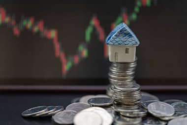 İş Parası, Mali ve Ev Konsepti. Arka planda küçük ev oyuncakları ve şamdan çizelgesi olan gümüş para yığınlarının yakınlaştırılması.