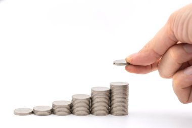 Para ve Tasarruf kavramı. İki bozuk para tutan adamın yakın plan fotoğrafı ve beyaz arkaplandaki gümüş sikkelerin en üste konması..