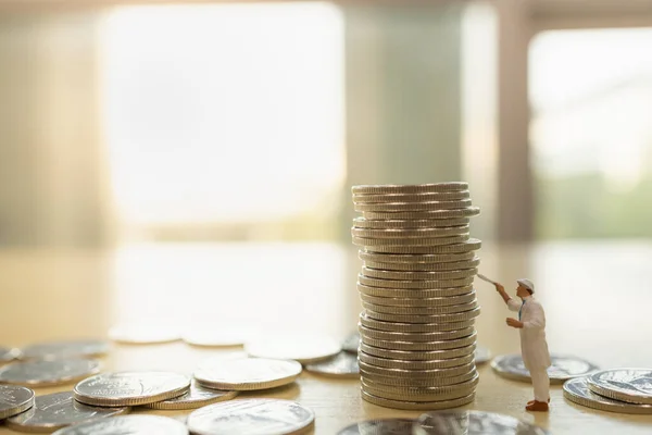 Business, Money and Financial Concept. Worker miniature figures people cleaning and painting stack and pile of coins with copy space.