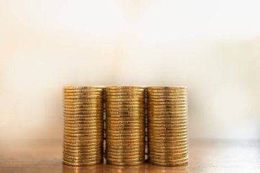 Money and Financial Concept. Closeup of three stack of gold coins on wooden table with copy space.