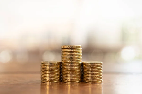 Money and Financial Concept. Closeup of three stack of gold coins on wooden table with copy space.