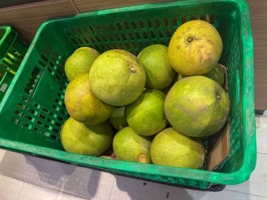 Doğal ışıklandırmayla dolu bir mağazanın rafındaki plastik sepetteki yeşil karpuzlar taze üretim pazarlama için ideal taze ve canlı bir atmosfer yaratıyor..