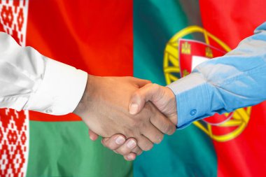 İki bayrağın arka planında iş tokalaşması. Beyaz Rusya ve Portekiz bayrağının arka planında erkek tokalaşması. Destek konsepti.