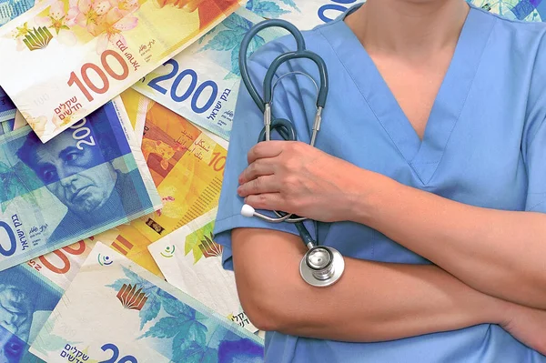 İsrail para destesinin arka planında steteskobu olan kadın cerrah ya da doktor. Ameliyat konsepti