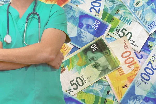 Male surgeon or doctor with stethoscope on the background of the Israeli shekel money stack. Health care and medical concept.