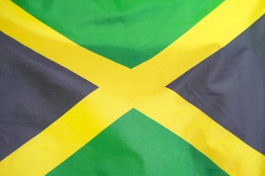 Jamaika 'nın kumaş desenli bayrağı. Jamaika bayrağı rüzgarda sallanıyor. Jamaika bayrağı birçok katlı bir spor kumaşı üzerine resmedilmiştir. Spor takımı afişi