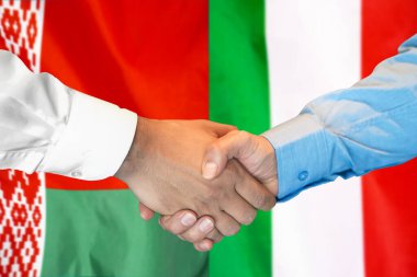İki bayrağın arka planında iş tokalaşması. Beyaz Rusya ve İtalya bayrağının arkasında erkek tokalaşması. Destek konsepti.