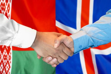 İki bayrağın arka planında iş tokalaşması. Beyaz Rusya ve İzlanda bayrağının arka planında erkek tokalaşması. Destek konsepti.