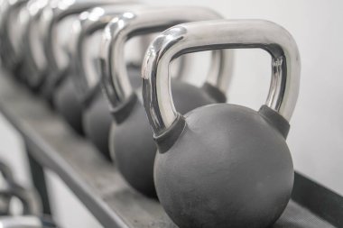 Farklı ağırlıklarda birkaç siyah ağırlık. Black Metal bir sıra ağırlık kaldırıyor. Spor kulübünde çaydanlık. Ağırlık Çalışması Ekipmanı