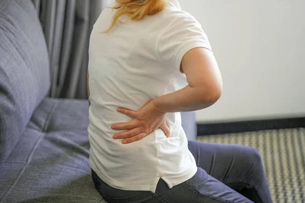 Woman suffer from low back pain. Hand of woman holding her waist backache in pain. Health care concept