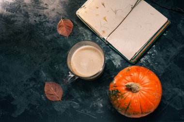 Bir balkabağı kabağı ve bitki bazlı yulaf ezmesi ya da boş not defterli badem sütü ile yapılmış latte kahve. Masada koyu mavi desenli fotokopi alanı çalışma konsepti üzerine.