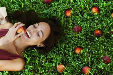 Beautiful happy young woman smiling eating a peach