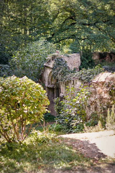 Stone gate of an old idyllic garden overgrown with plants
