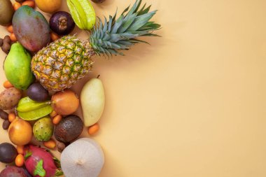 Bej bir arka planda tropikal meyvelerin karışımı. Tasarım için yeri var. Egzotik sağlıklı yiyecekler. Mevsimlik organik çiğ meyve. Bej bir arkaplanda izole edilmiş.