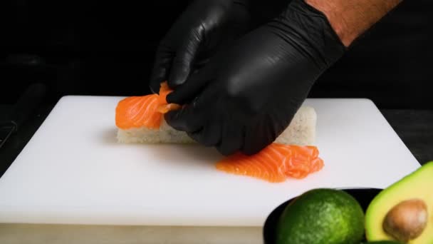 老大的手把鲑鱼片放在寿司上.在家庭厨房做寿司。制作亚洲寿司的过程。东方食品。自制寿司。4K. — 图库视频影像