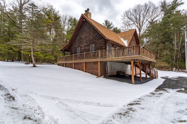 Bethel, New York / ABD 18 Şubat 2025: Kış boyunca Sullivan County 'de etrafı kar ve yemyeşil ağaçlarla çevrili taşralı ahşap kulübe.