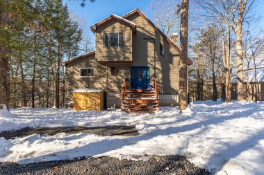 Poconos Pennsylvania ABD 12 Şubat 2025: Kar, sakin bir dağ mahallesindeki kış ağaçlarıyla çevrili meskenleri kapladı.