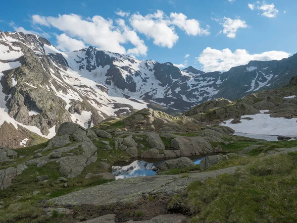 Θέα από Bremer Hutte με λίμνη από τήξη γλώσσες χιόνι και χιονισμένα βουνοκορφές, καταπράσινο λιβάδι, γαλάζιο ουρανό backgound. Αργά άνοιξη ηλιόλουστο απόγευμα, ζωντανά χρώματα — Φωτογραφία Αρχείου